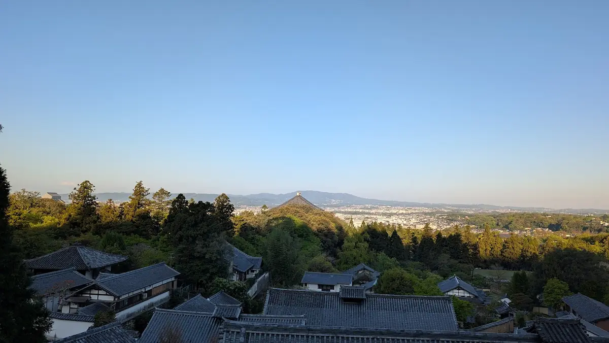 東大寺二月堂の舞台（バルコニー）から見下ろす奈良市内の全景。早朝の光に照らされたお寺の屋根並みと遠くの山々