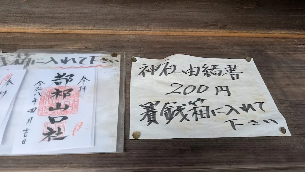 都祁水分神社の御朱印案内。神社由緒書が200円であることや、代金は賽銭箱に入れるようにとの手書きの指示が掲示されている