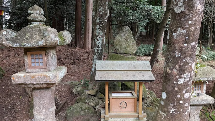 都祁水分神社の境内にある白龍大神の祀り場。苔の付いた古い石灯籠と、自然石に「白龍大神」と刻まれた碑、手前には小さな木造の祠が並んでいる