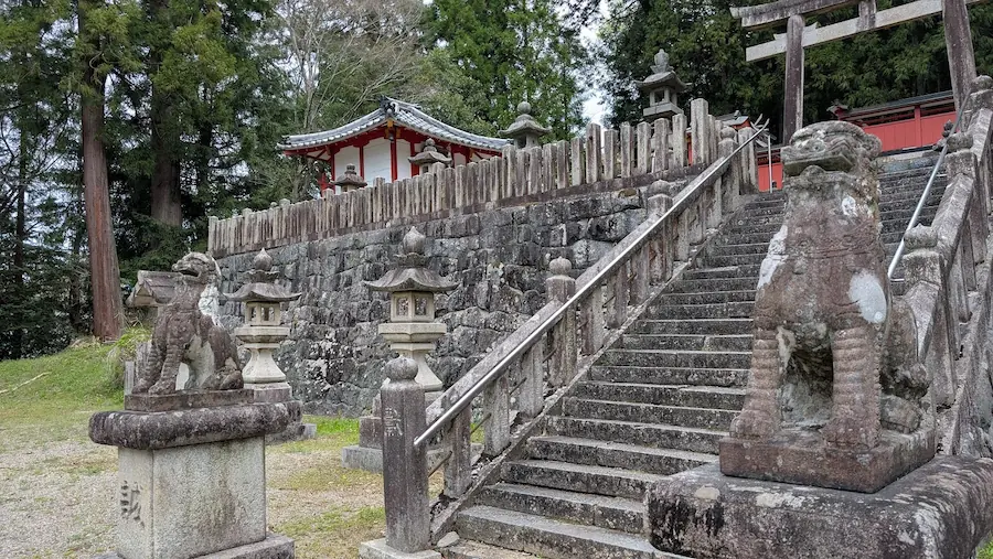 宇陀・春日神社の石段前に鎮座する、珍しい姿の狛犬。胸を大きく張り、背中を弓なりに反らせた独特のポーズをとっており、長い年月を感じさせる苔が体の一部を覆っている。