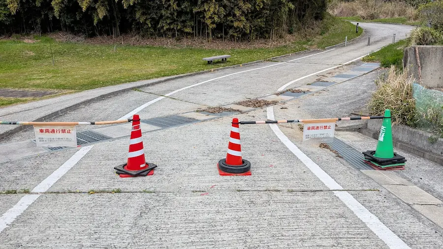 宇陀松山城跡の駐車場から下った場所にある車両通行禁止のゲート。赤いカラーコーンとバーが設置され、「車両通行禁止」の案内が掲げられている。
