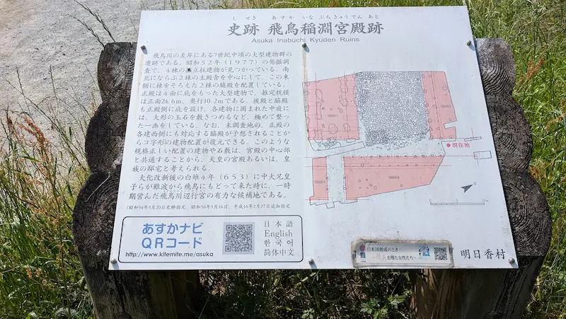 飛鳥稲渕宮殿跡の歴史と建物配置図が記載された解説板。あすかナビQRコードも併記されている。