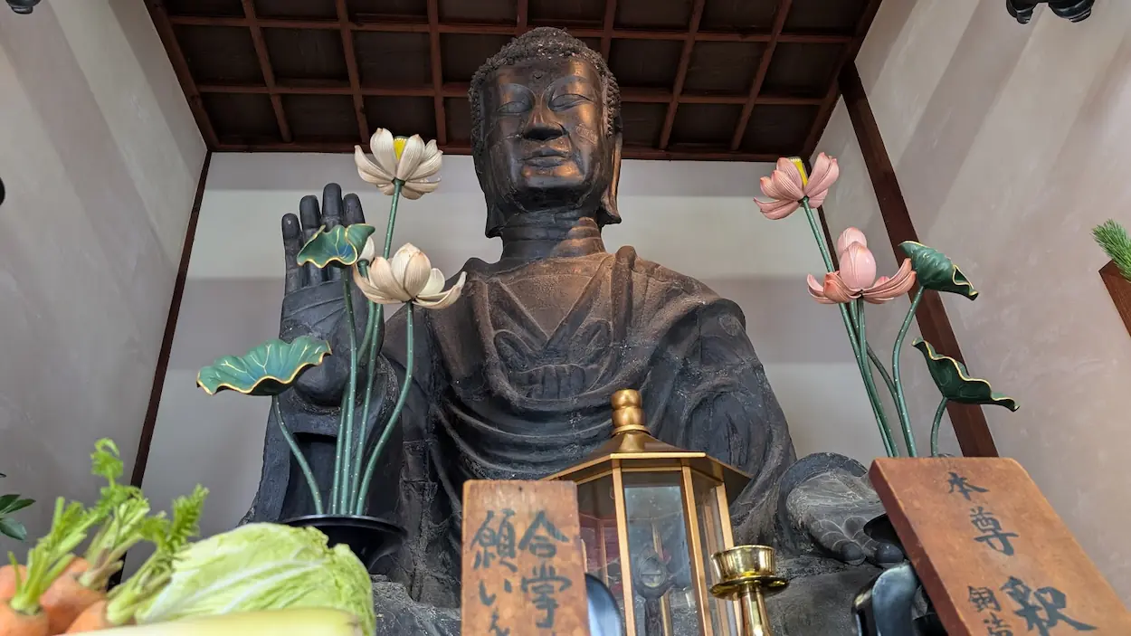 飛鳥寺の本尊である飛鳥大仏。銅造釈迦如来坐像が安置され、手前には供えられた野菜が見える
