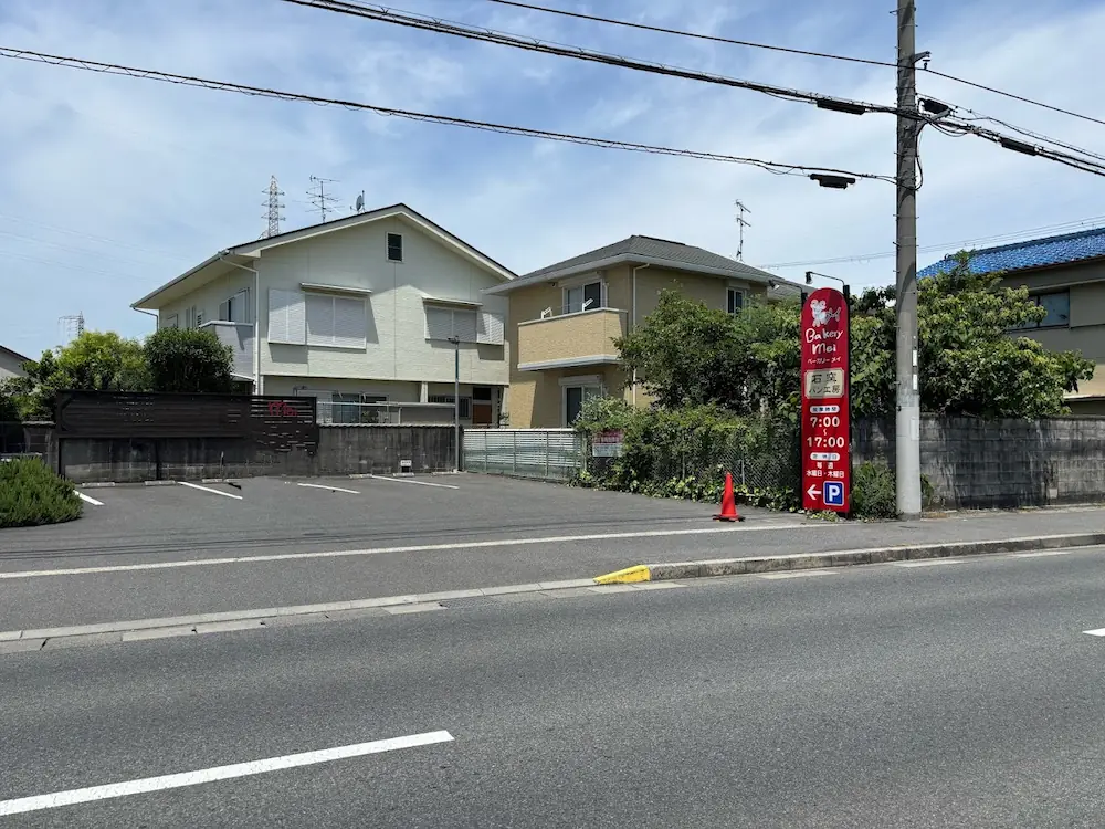 大和高田市の県道沿いにある、ベーカリーメイの専用駐車場。赤い看板が目印の平坦で入りやすい駐車スペース。