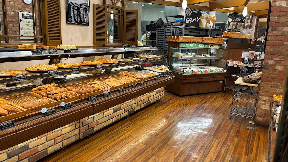 キャパトル真美ヶ丘店の店内。木目調の床とレンガの壁に囲まれた、焼きたてのパンが並ぶ広々とした売り場