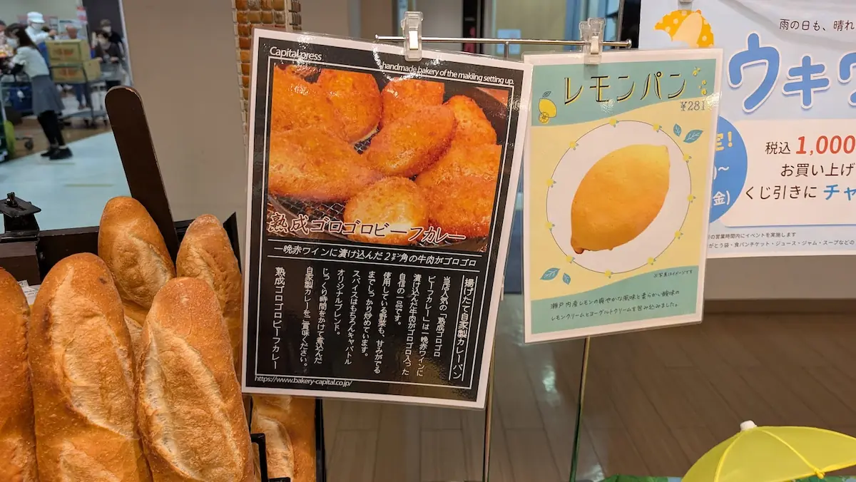 キャパトル真美ヶ丘店の店頭看板。一晩赤ワインに漬け込んだ牛肉が特徴の「熟成ゴロゴロビーフカレー」と「レモンパン」を紹介している様子