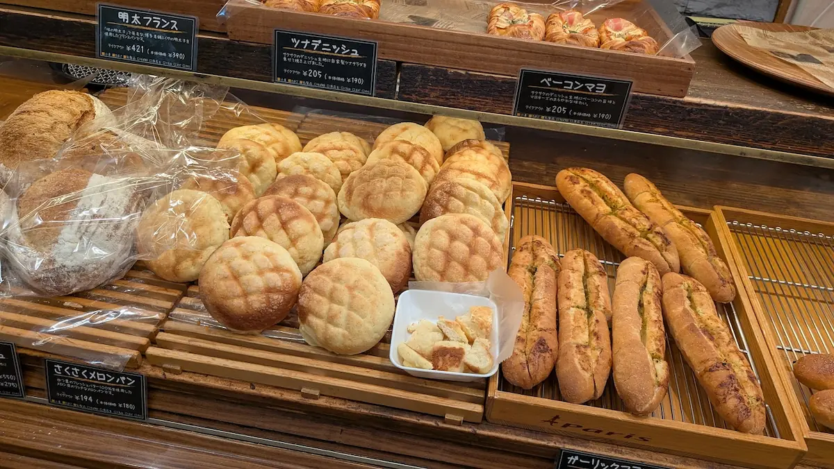 キャパトル真美ヶ丘店の店頭に並ぶメロンパンやガーリックフランスと、試食用として置かれたカットされたパンの様子