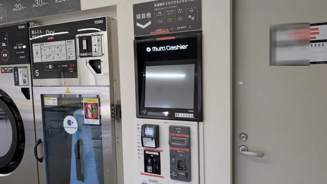コインランドリー クリーンアップ店内の精算機と敷布団専用乾燥機。現金のほか電子マネー等にも対応した精算機と、敷布団専用の乾燥機が並んでいる様子