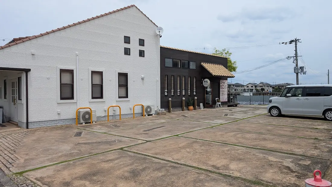 広陵町の「大仏カフェ」の店舗外観。白と黒の外壁が特徴的な建物と、広々とした駐車場の様子