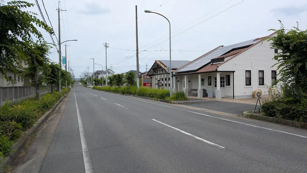 香芝方面へと続く道路沿いに佇む、大仏カフェ。自然な緑と白黒のモダンな外壁が調和する心地よい風景