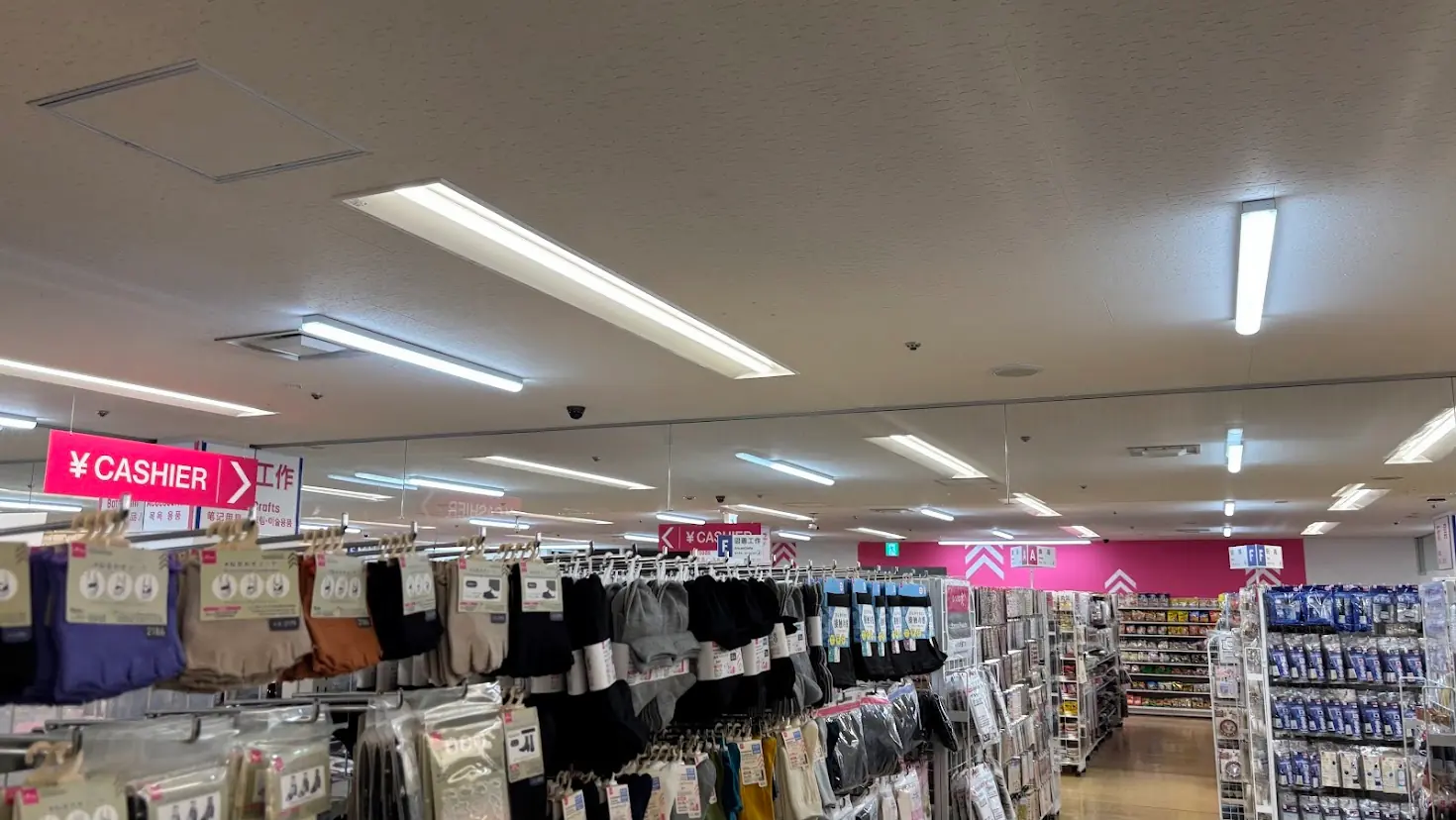 近鉄百貨店橿原店のダイソー店内。レジへの案内板や、衣料品・日用品などが豊富に並ぶ通路の様子