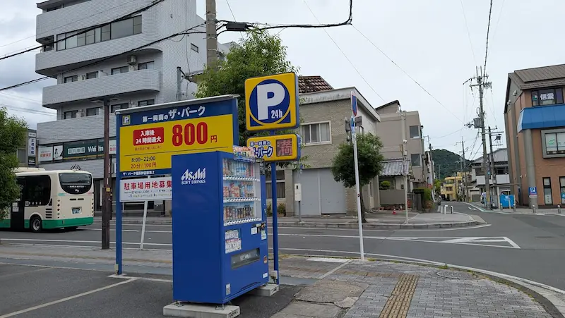 橿原神宮前駅西口近くにある、24時間最大800円のコインパーキング「ザ・パーク」の料金案内看板と設置された自動販売機