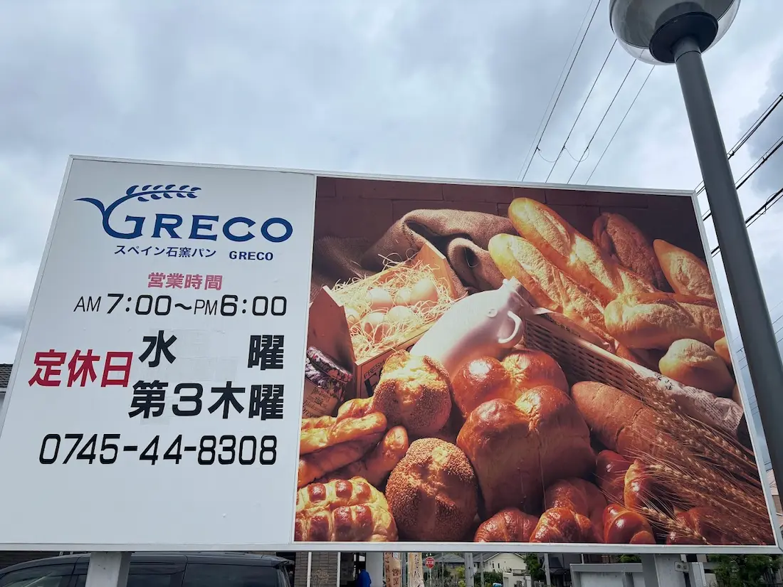 奈良県広陵町の「スペイン石窯パン GRECO」の看板。営業時間と定休日が記載されている