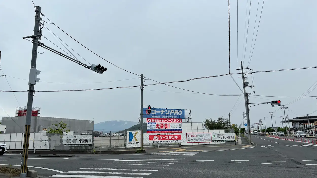 桜井市の建設現場に掲示されたケーズデンキのオープン告知バナーや、関連企業の看板が並ぶ風景