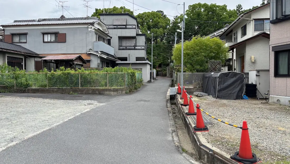 久米寺へと続く住宅街の狭い道。三角コーンが並べられ、道幅に注意が必要なアクセス路の様子