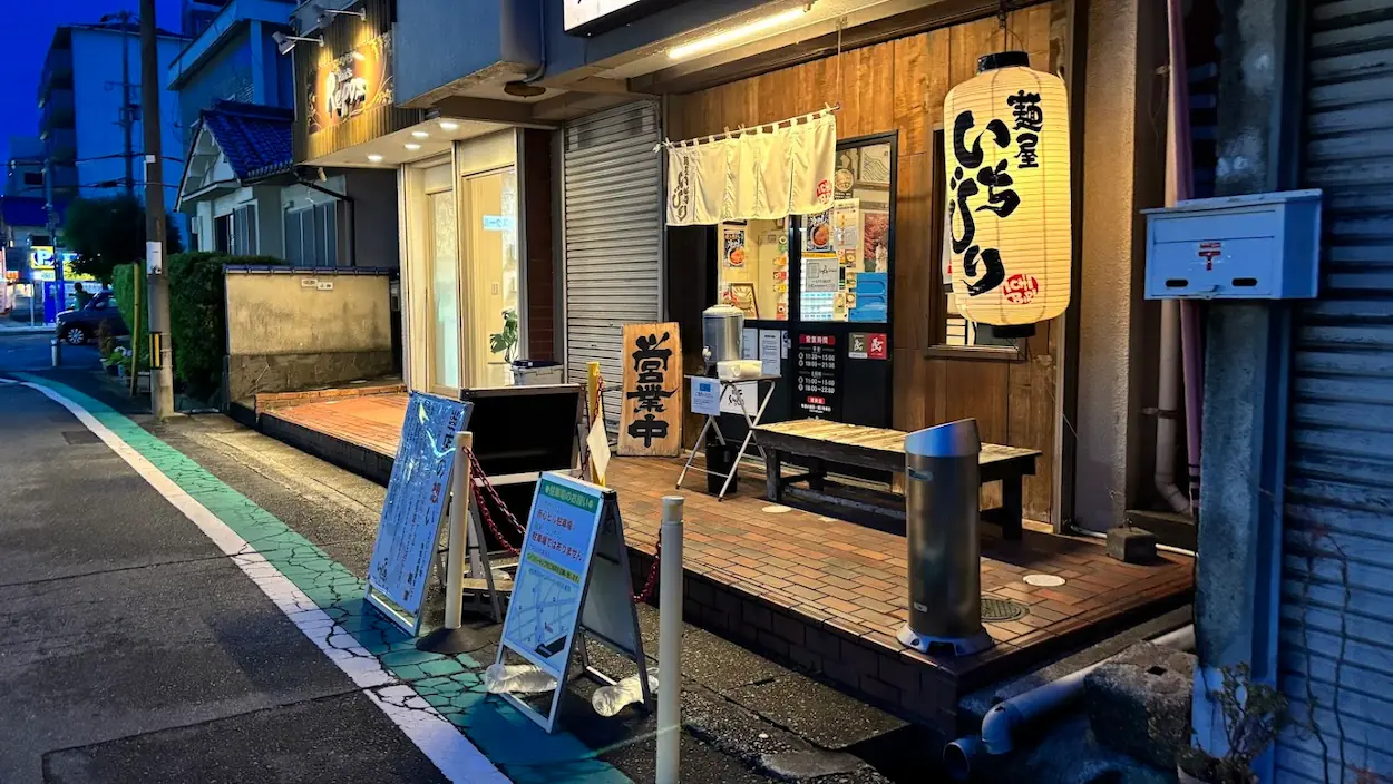 奈良の「麺屋いちびり」の店舗外観。提灯が灯り、駐車場に関する案内看板が置かれた夜の様子