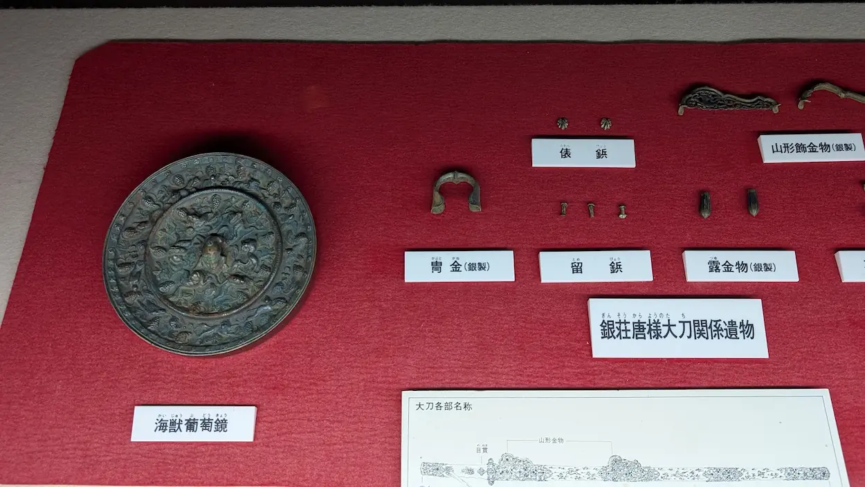 高松塚壁画館に展示されている「海獣葡萄鏡」と「銀荘唐様大刀関係遺物」などの副葬品
