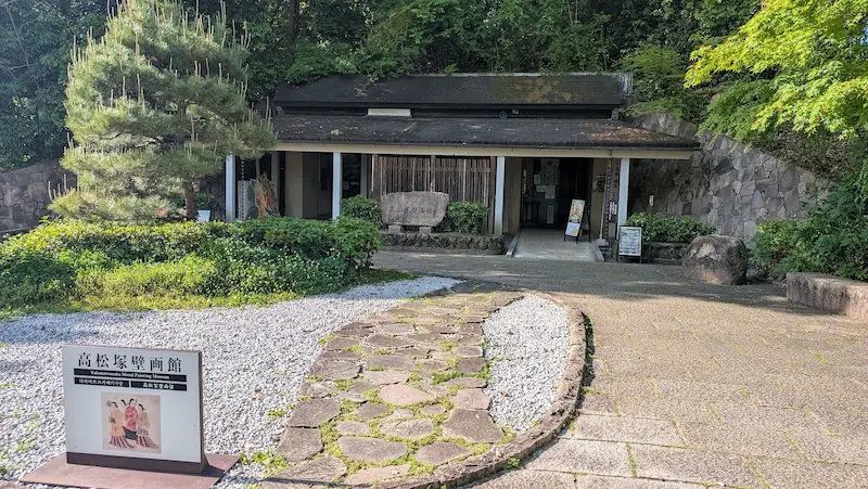 高松塚壁画館の入り口。手前に案内板が設置され、石畳の通路が建物へと続く様子