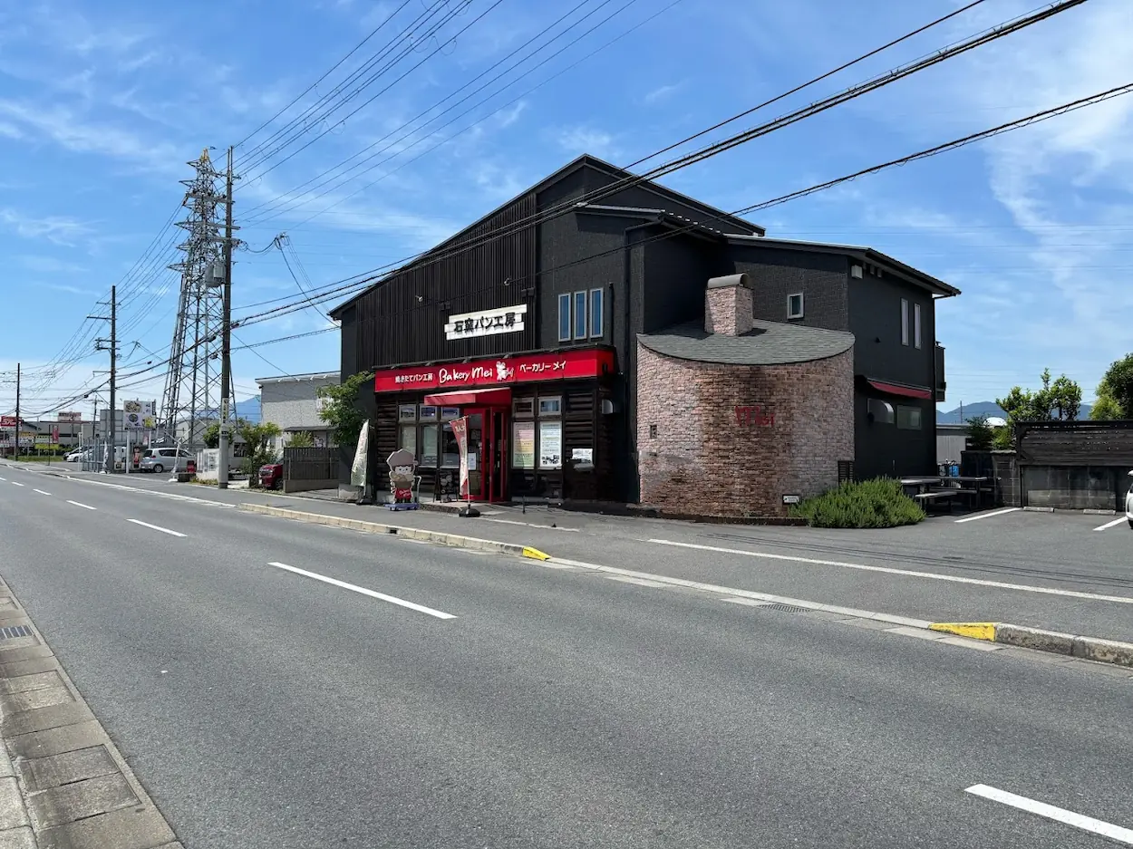 大和高田市の県道沿いに佇む、黒い外壁とレンガ造りの煙突が特徴的なパン屋「ベーカリーメイ」の全景。
