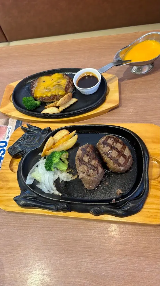 ビッグボーイで提供される大俵ハンバーグとチーズハンバーグ。牛の形をした鉄板に乗った大俵ハンバーグと、とろけるチーズがのったハンバーグが並んでいる様子