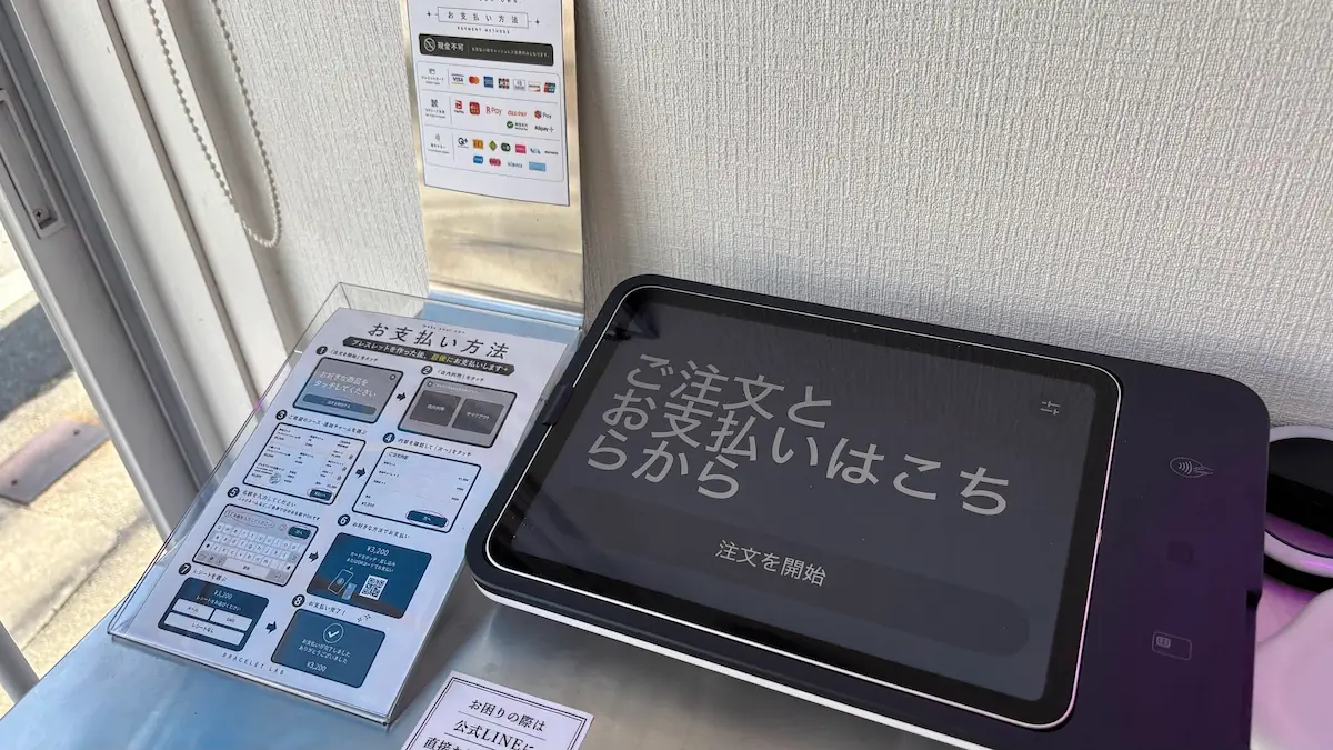 「BRACELET LAB.」の店内に設置されたキャッシュレス決済用のタッチパネル端末と、利用手順および対応しているクレジットカードやQRコード決済のマークが掲示されている様子。