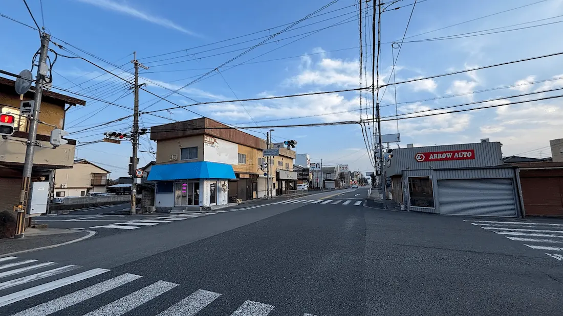 「BRACELET LAB.」の店舗前交差点から奈良方面へ向かう道路の様子。遠方にパチンコ123やツインゲートの看板、周辺の建物や電線が写っている。