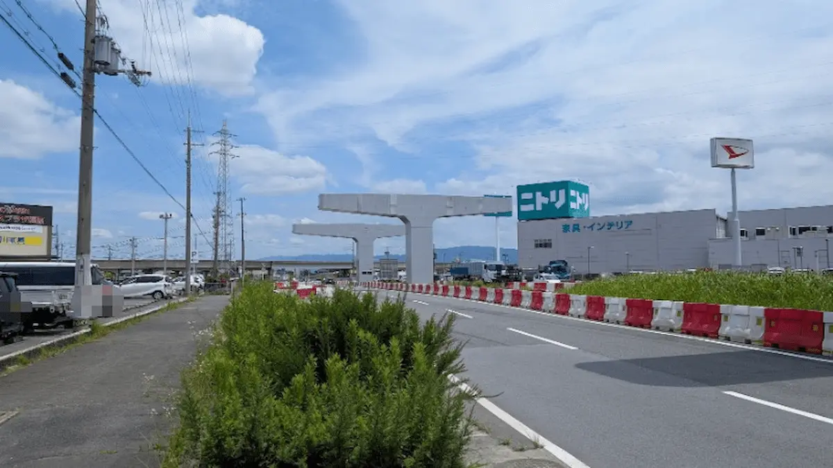 中和幹線方面を望む景色。建設中の道路構造物と、大型家具・インテリア店「ニトリ」の看板が見える風景