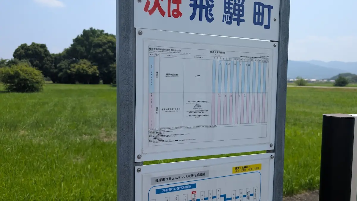 「橿原市藤原京資料室前」バス停に掲示されている、平日の運行スケジュールや行先(橿原市昆虫館など)が記載された詳細な時刻表のアップ。