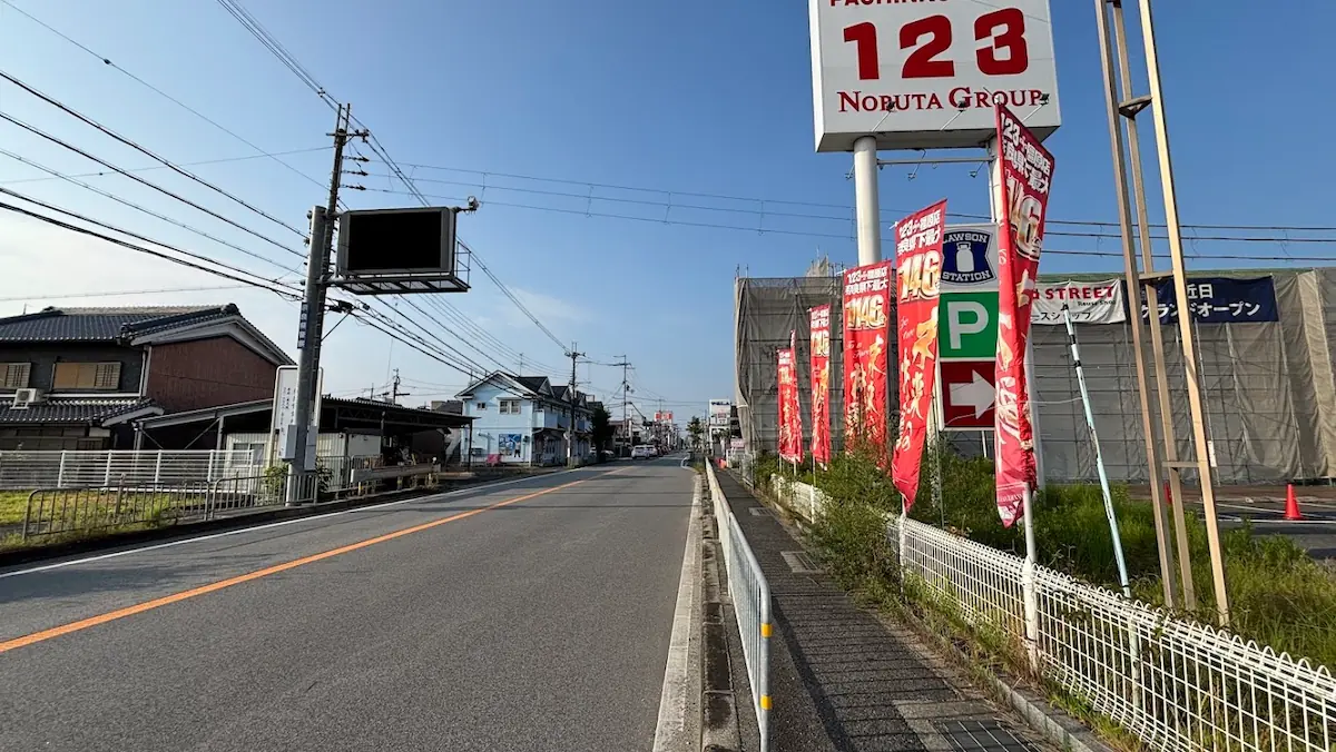 パチンコ店の看板やのぼりが並ぶ歩道と、片側1車線の道路が橿原市八木方面へまっすぐ伸びている様子。