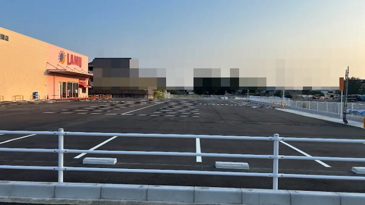 ラ・ムー橿原醍醐店の店舗脇に広がる、白線が引かれたばかりの非常に広い駐車スペース。奥には店舗の入り口や周辺の建物が見える
