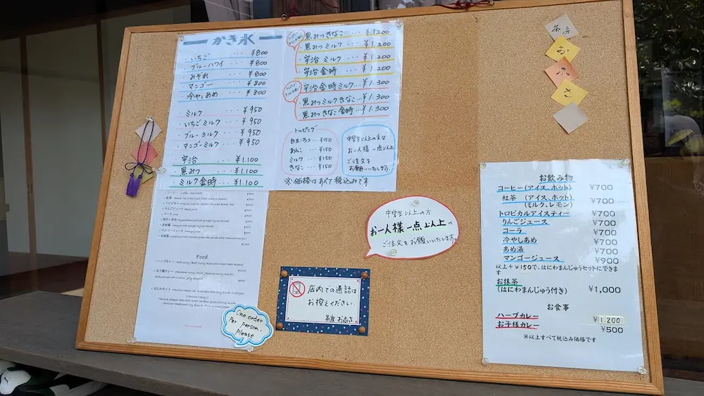 おふさ観音の茶房「茶房おふさ」のメニュー表ボード。かき氷、ドリンク、お食事のメニューや価格が手書きやプリントで掲示されている
