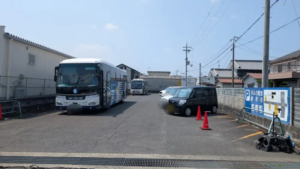平日の午前10時頃のおふさ観音第二駐車場。大型バスや普通自動車が駐車しており、右側には「おふさ観音 参拝者駐車場」の青い案内看板が掲げられている