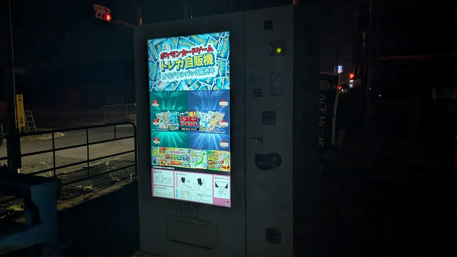 夜間に稼働している「ポケモンカードゲーム トレカ自販機」。オリジナルパックが販売されており、タッチパネルで決済方法などが表示されている