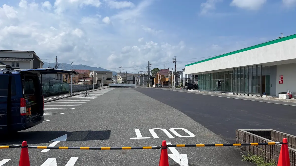 建設中の店舗に隣接する、広々とした駐車場の風景。整備されたアスファルトと店舗の外観が写っている