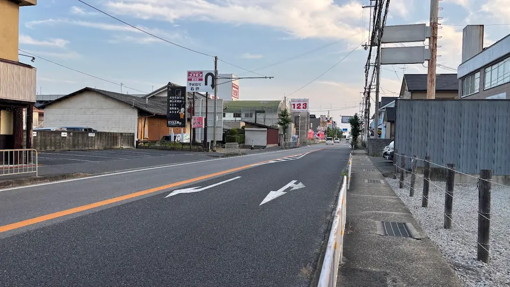 「とり夢亭」の横の北側にある1台分の駐車スペースと、店舗の入り口付近の様子が写る道路沿いの景色。