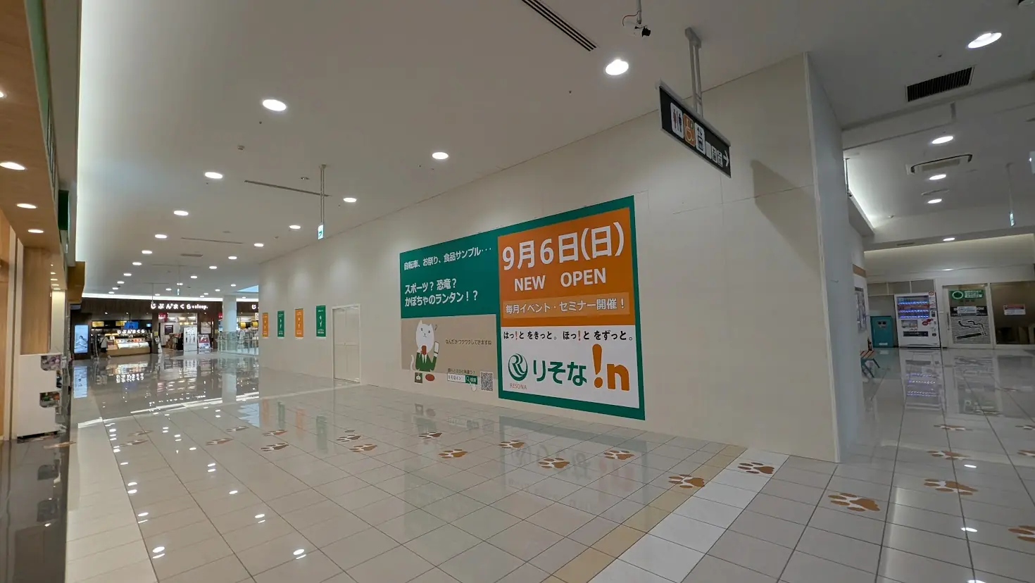 イオンモール橿原（アルル）内で、9月6日オープン予定の「りそな!n」の告知ポスターが掲示された通路とオープン予定地の様子。