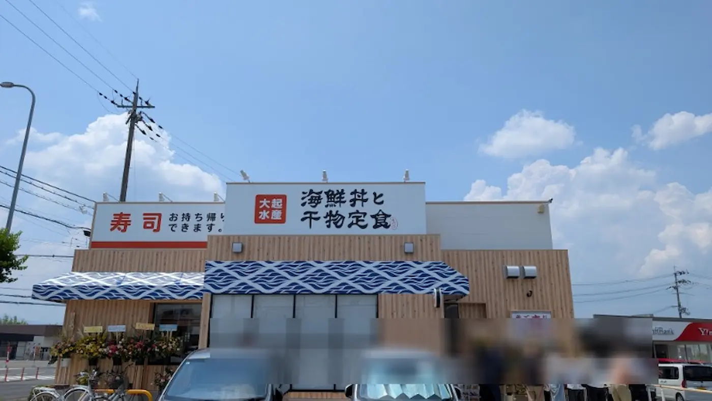 8月3日に新しくオープンしたフレスポ桜井にある「大起水産 海鮮丼と干物定食」の店舗外観。青空の下、開店祝いの花輪が飾られ、車や人が集まっている様子。