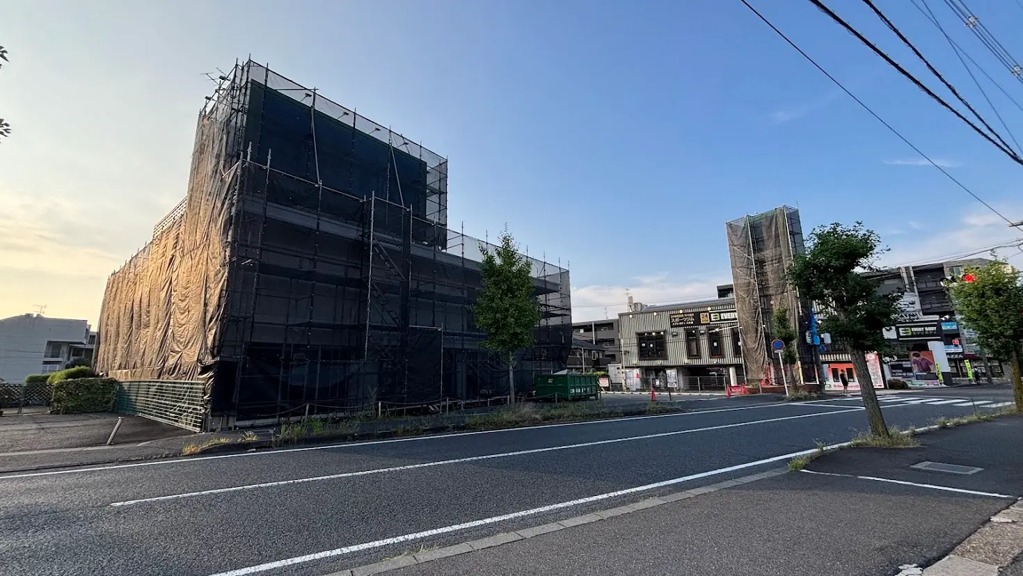 青空の下、全面に黒い養生メッシュと工事の足場が組まれた橿原市の旧ダイソー店舗の全景外観。