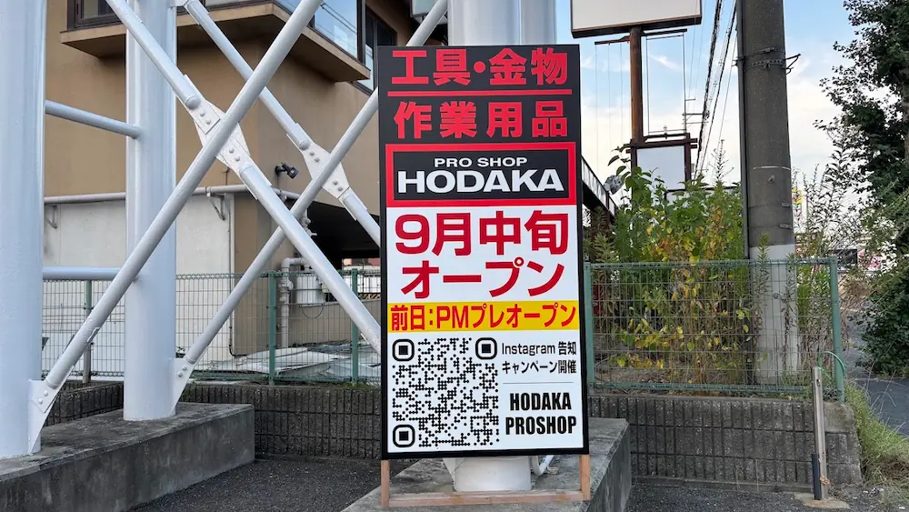 「PRO SHOP HODAKA」のロゴとともに「9月中旬オープン」やInstagramのQRコードが記載された、工具・金物・作業用品店の立て看板のアップ。