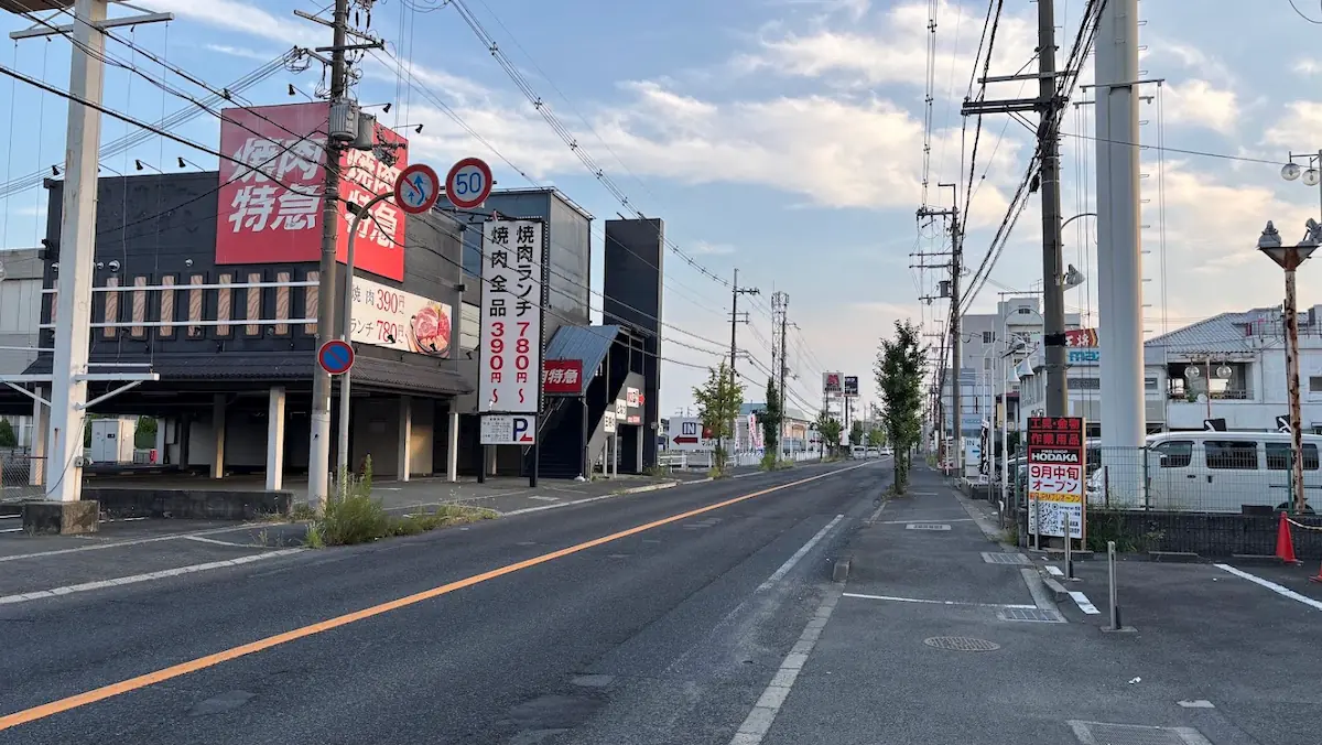 青空の下、奈良県橿原市のロードサイドにある「焼肉特急」の店舗外観と、そこから奈良方面へと延びる道路の景観。