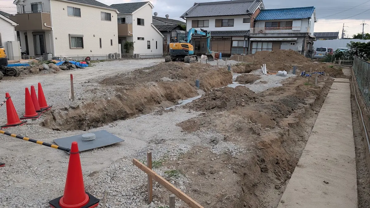 広陵町の工事現場で、基礎工事に向けて地面が深く掘削され、土砂や配管の基礎部分がむき出しになっている様子。