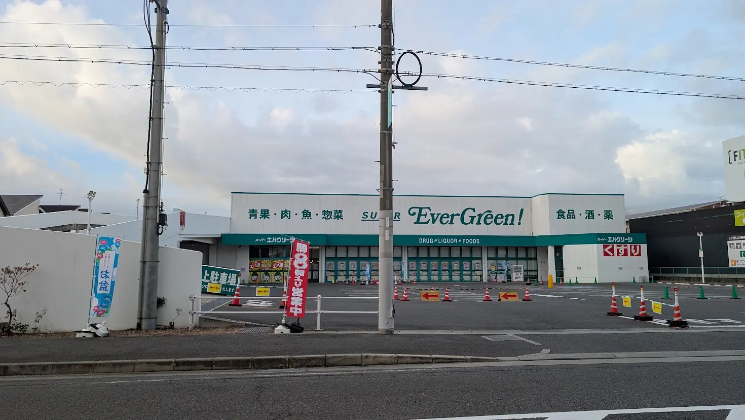 夕暮れの空の下、緑と白を基調とした建物と「SUPER EverGreen!」の看板、広い駐車場が広がる広陵町のエバーグリーンの外観。