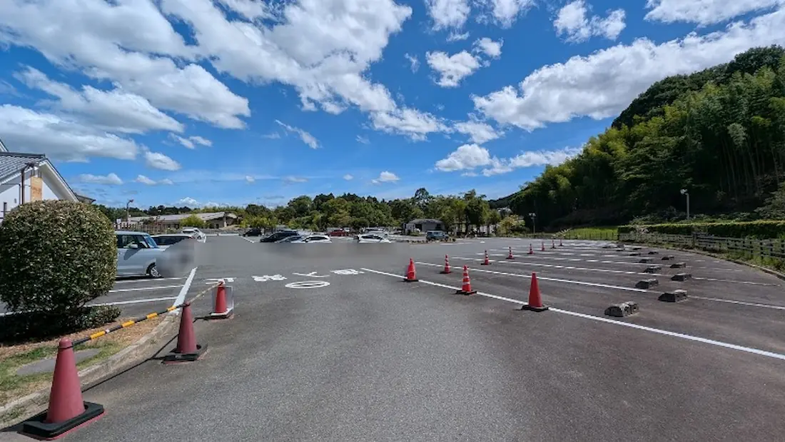 青空の下、白線とカラーコーンが整備された奈良県立万葉文化館の広々とした駐車場の様子。数台の車が駐車されており、混雑が落ち着いた雰囲気が伝わる。