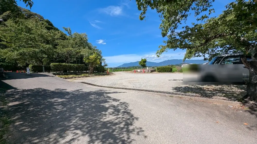 青空の下、木々の木漏れ日が差し込む奈良県明日香村の橘寺の駐車場と周辺のアクセスの様子。