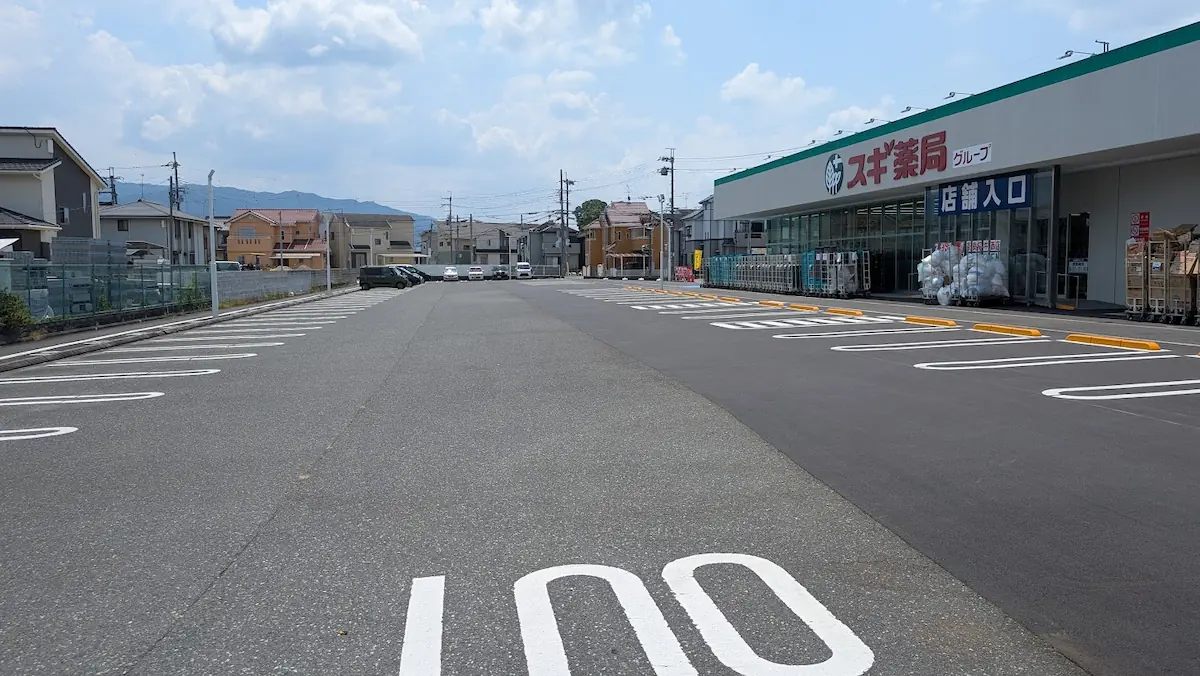 青空の下、桜井市に新しくオープンするスギ薬局の店舗前に広がる、白線が整備された広々とした駐車場の全景。