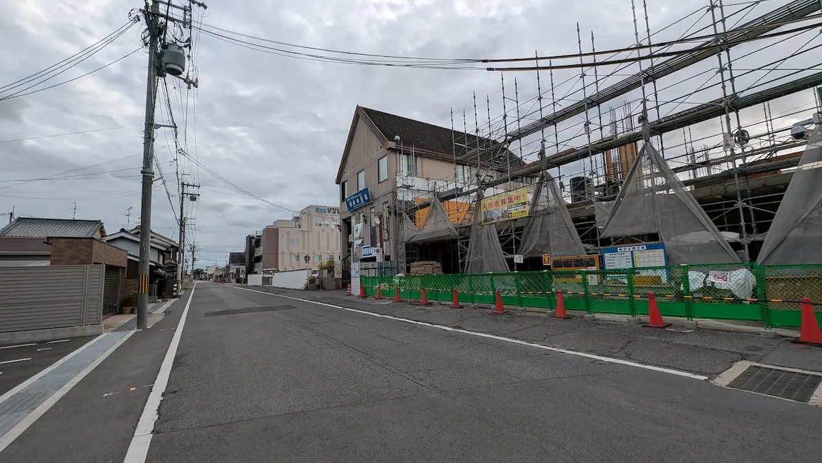 橿原市四条町のマンション建設現場付近から今井町方面へ向かって伸びる車道と、沿道にある「横田寿司」や「平成記念病院」周辺の街並みの様子。