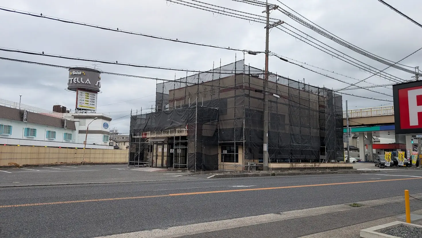 曇天の下、黒い足場と防音シート(黒幕)に覆われた建物。9月中旬オープン予定の「天下一品」の改装工事が進む橿原市曲川町の店舗外観と周辺駐車場の様子。