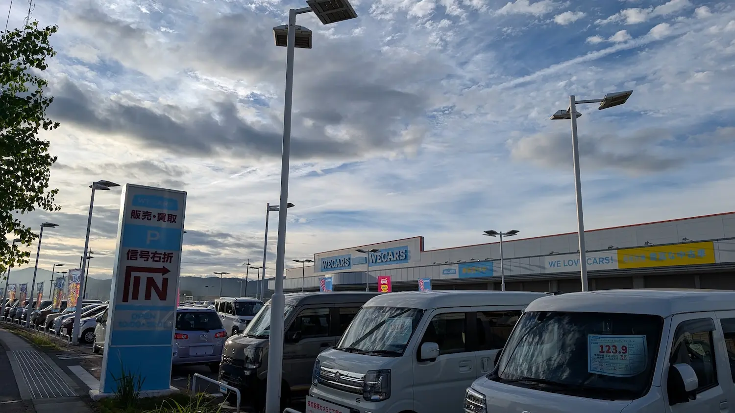 中和幹線沿いにある「WECARS（ウィーカーズ）」の店舗外観。多数の中古車が並ぶ展示スペースや看板の様子。
